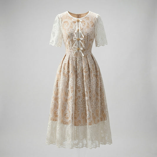 Close-up of Evie champagne midi dress featuring white floral lace, scalloped hem, and white ribbon lace-up bodice with gold beads.