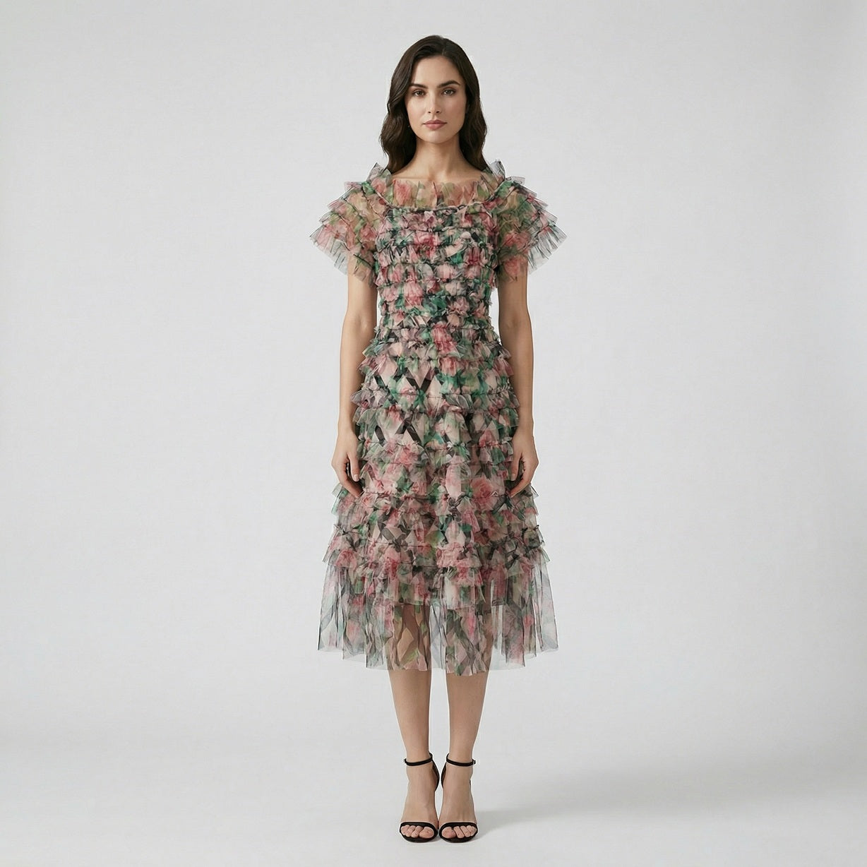 Model wearing the Amy Floral Midi Dress in light pink and green tiered tulle with an off-the-shoulder ruffled neckline.