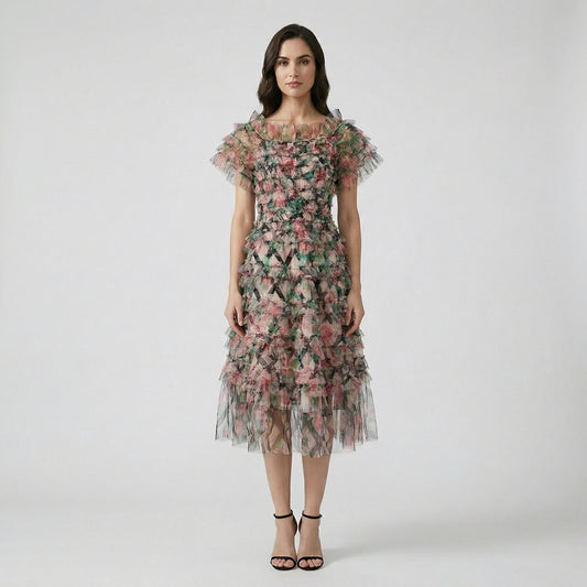 Model wearing the Amy Floral Midi Dress in light pink and green tiered tulle with an off-the-shoulder ruffled neckline.