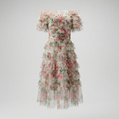 Model wearing the Amy Floral Midi Dress in light pink and green tiered tulle with an off-the-shoulder ruffled neckline.