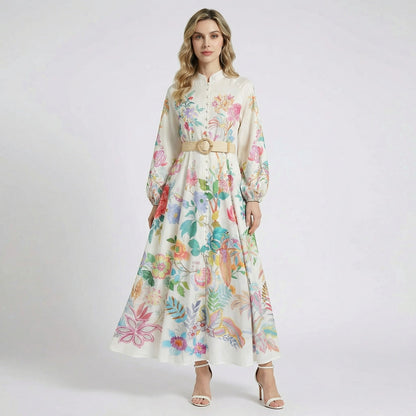 Arina white long-sleeve maxi dress with vibrant floral and bird prints, featuring a mandarin collar and a tan woven buckle belt.