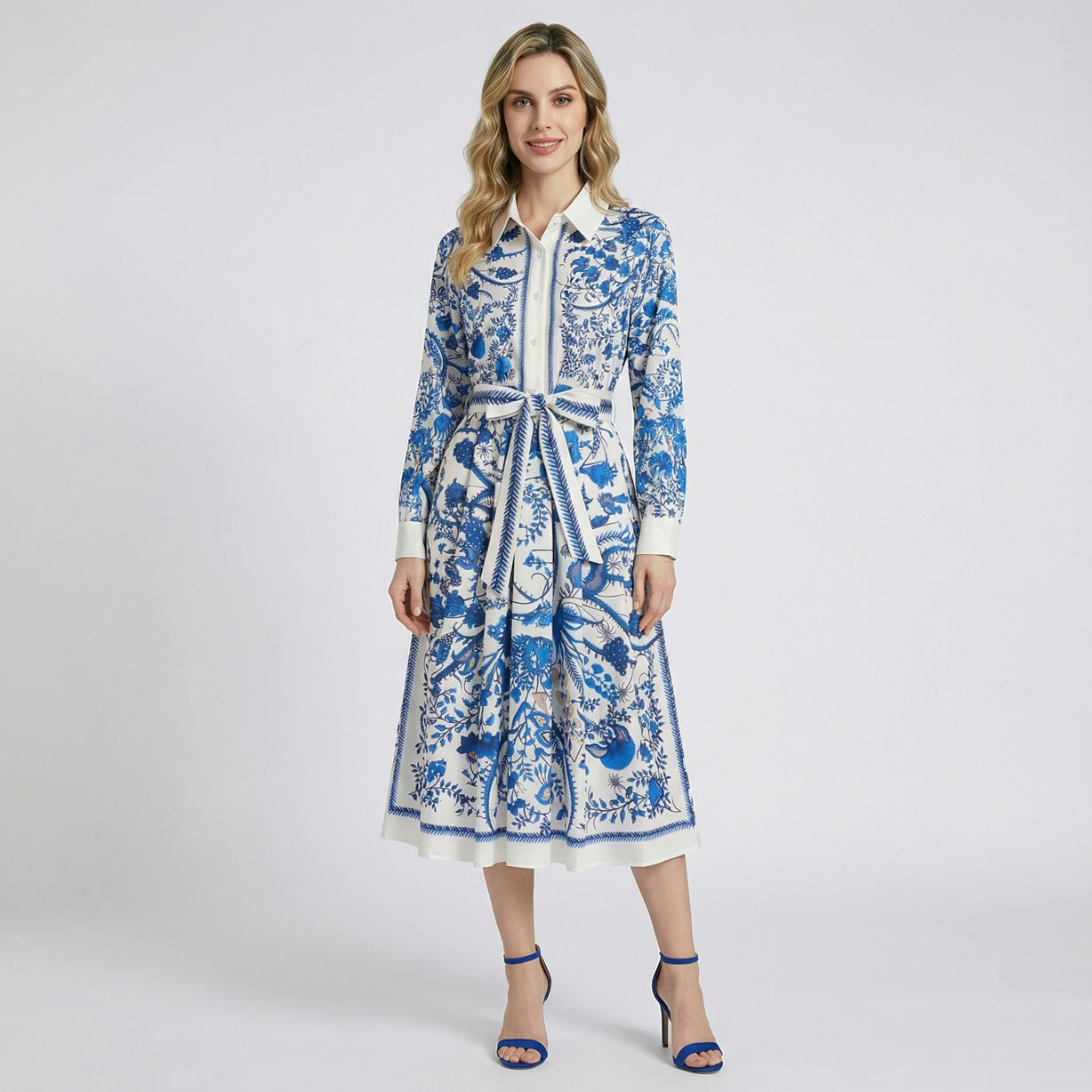 Model wearing the Aurora 115cm blue floral toile midi shirt dress with long sleeves and a matching waist sash against a white background.