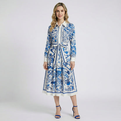Model wearing the Aurora 115cm blue floral toile midi shirt dress with long sleeves and a matching waist sash against a white background.