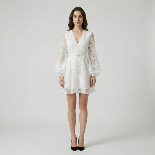 White floral lace mini dress with long puff sleeves and pearl buttons on a flat lay background