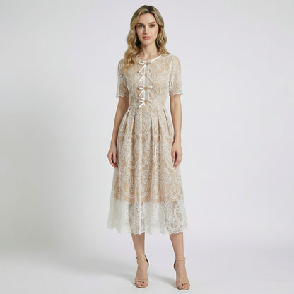 Close-up of Evie champagne midi dress featuring white floral lace, scalloped hem, and white ribbon lace-up bodice with gold beads.