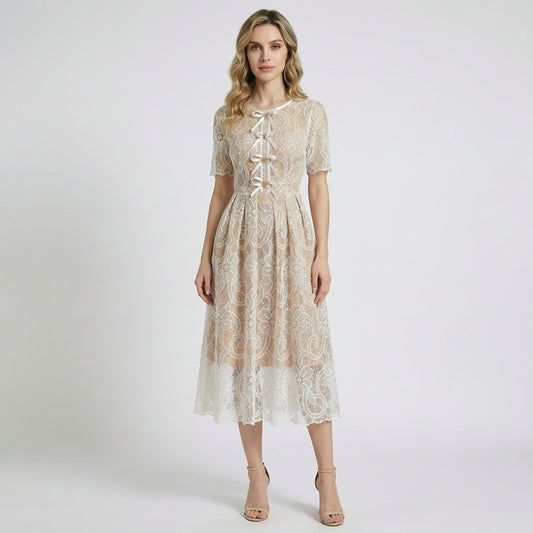 Close-up of Evie champagne midi dress featuring white floral lace, scalloped hem, and white ribbon lace-up bodice with gold beads.