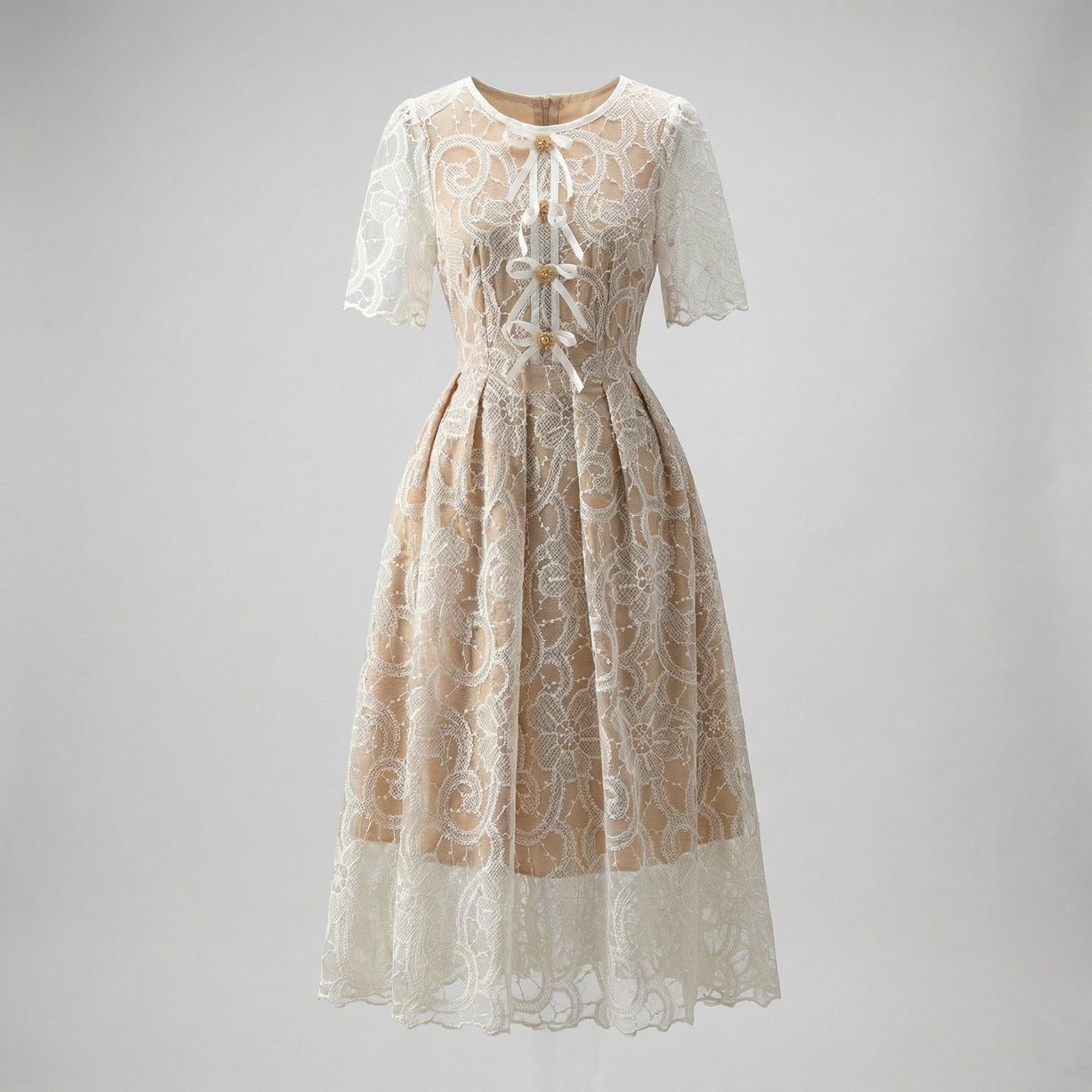 Close-up of Evie champagne midi dress featuring white floral lace, scalloped hem, and white ribbon lace-up bodice with gold beads.