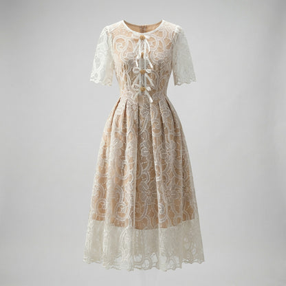 Close-up of Evie champagne midi dress featuring white floral lace, scalloped hem, and white ribbon lace-up bodice with gold beads.