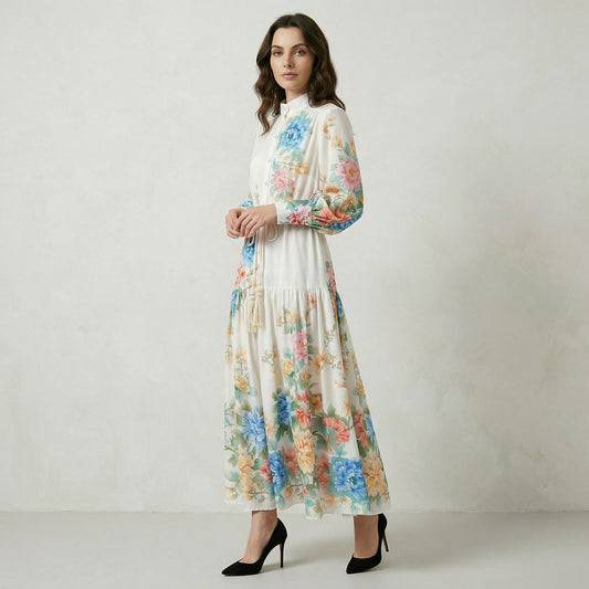 Cream-colored Fiorella maxi dress with colorful blue and pink floral print, featuring lantern sleeves and a tassel waist rope.