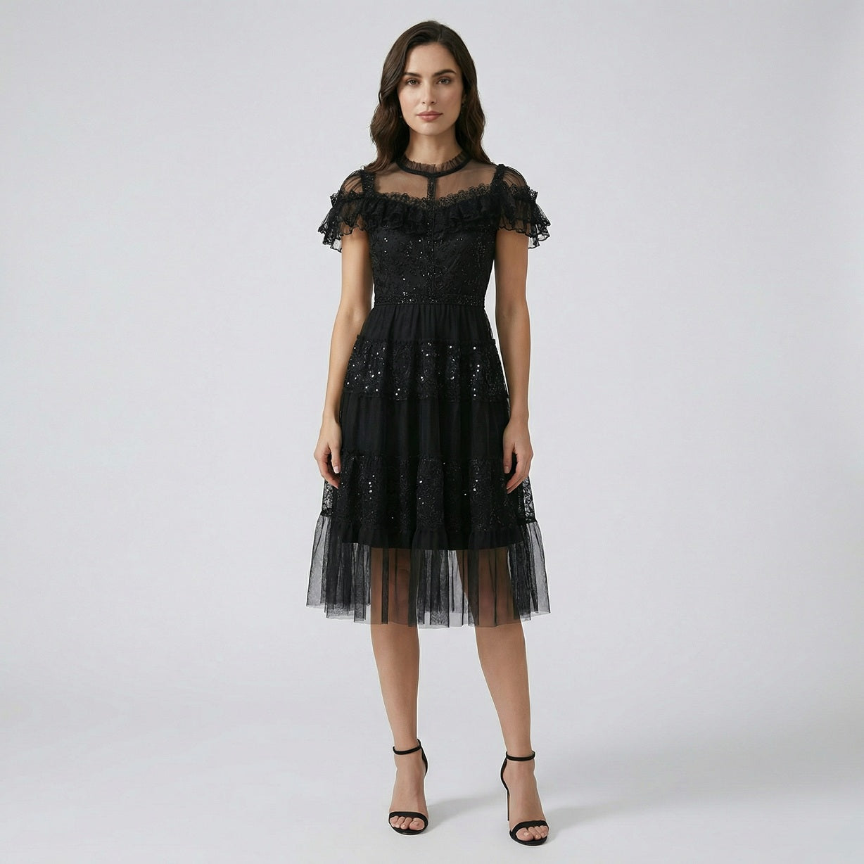 Model wearing Flavia black sequin tulle dress with tiered skirt and ruffled lace neckline.