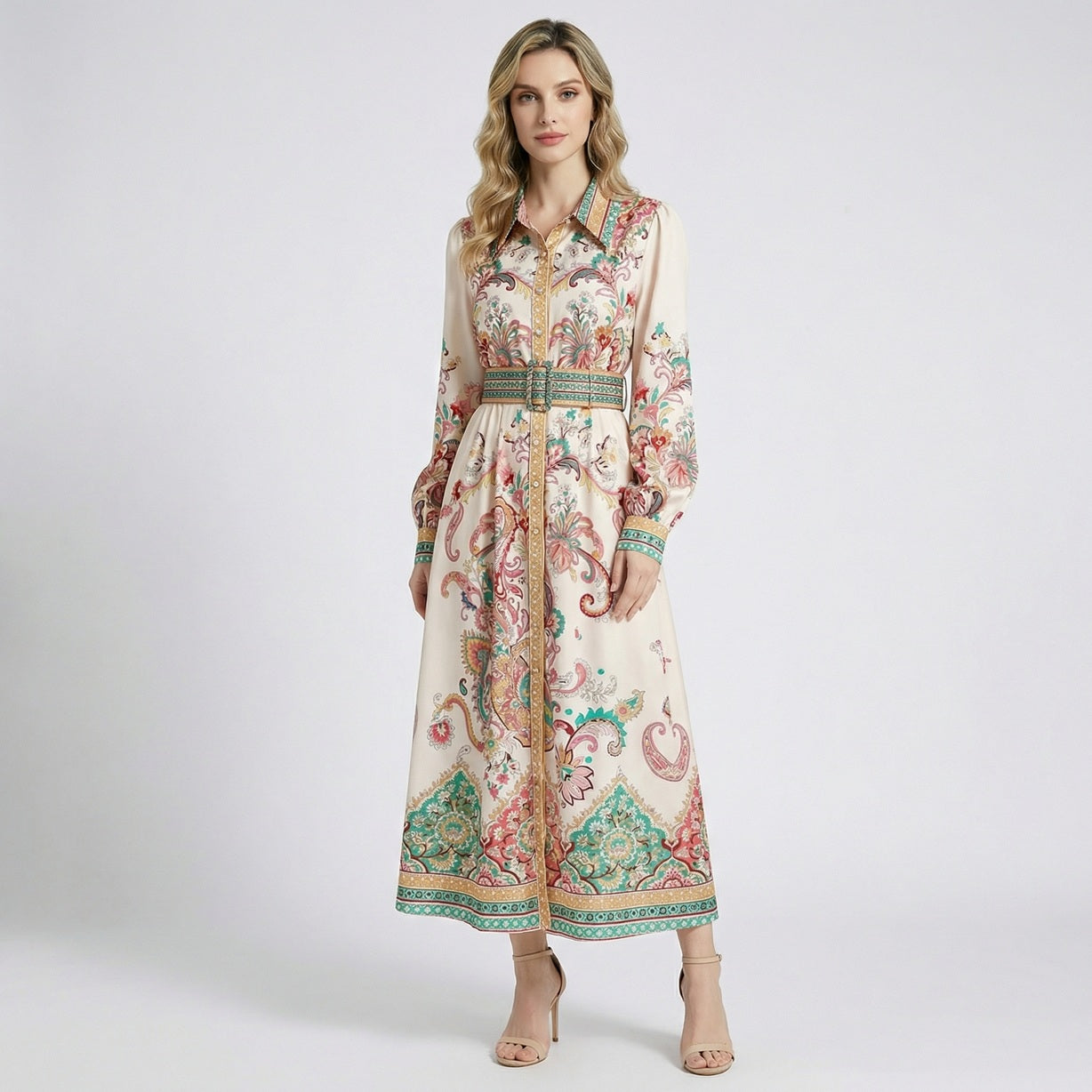 Front view of a woman wearing the Gail maxi dress, a cream-colored long-sleeve shirt dress with teal and coral paisley patterns and a matching belt.