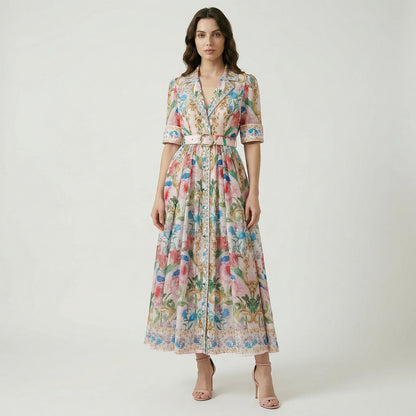 The Judith Maxi Dress in cream and navy featuring a floral baroque print, notched collar, button-down front, and a matching gold buckle belt on a flat lay display.