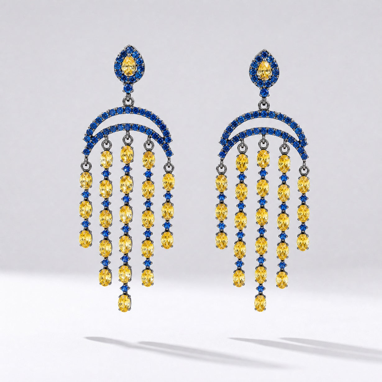 Pair of Leah geometric drop earrings featuring tiered blue and yellow cubic zirconia stones in a black gold setting.