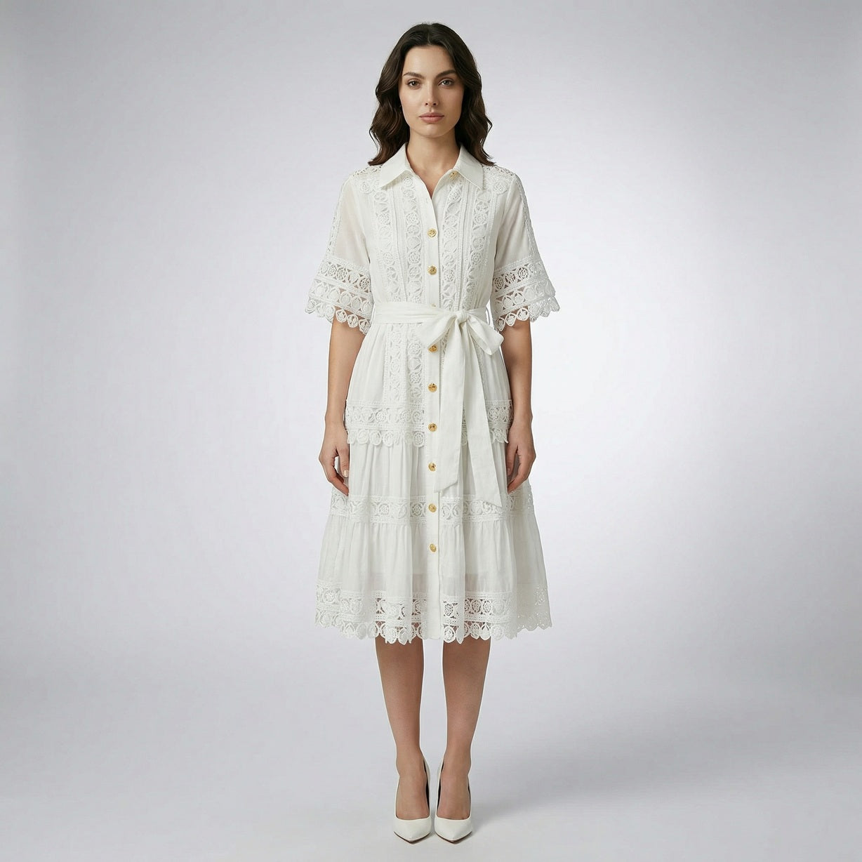 The Noora midi dress shown in black, white, sage green, and camel featuring intricate lace panels, gold buttons, and a matching belt.