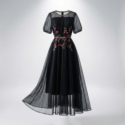 Front view of Sara midi-maxi dress in black and white featuring red floral embroidery, mesh sleeves, and a silver leaf belt