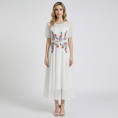 Front view of Sara midi-maxi dress in black and white featuring red floral embroidery, mesh sleeves, and a silver leaf belt