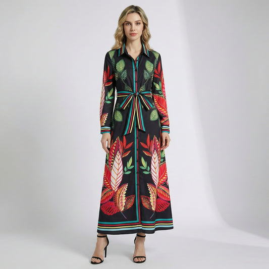Serena long sleeve maxi shirt dress with bold red and green tropical botanical print on black fabric, featuring a striped waist belt and structured collar.