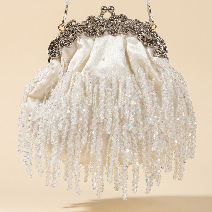 Teodora vintage-style white cream evening clutch featuring shimmering beaded fringe and an ornate silver metal filigree frame with a pearl chain.