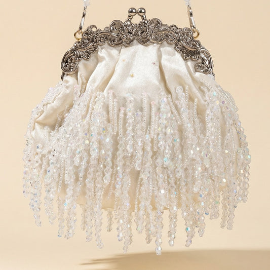 Teodora vintage-style white cream evening clutch featuring shimmering beaded fringe and an ornate silver metal filigree frame with a pearl chain.