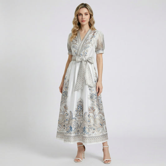 Two Teodora maxi dresses in black and white featuring paisley prints, puff sleeves, and large bow belts.