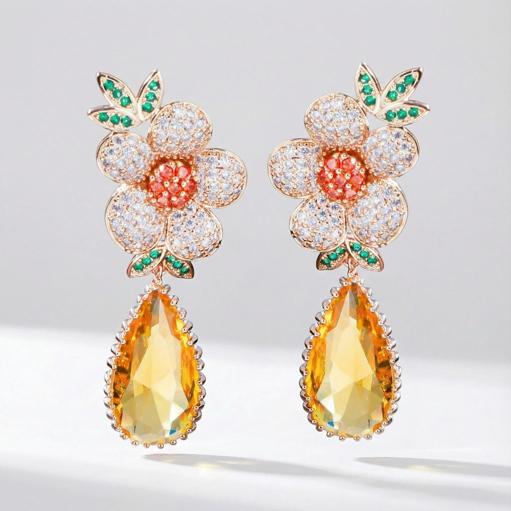 Victoria floral cubic zirconia drop earrings with white petals, orange center, green leaves, and yellow crystal drop