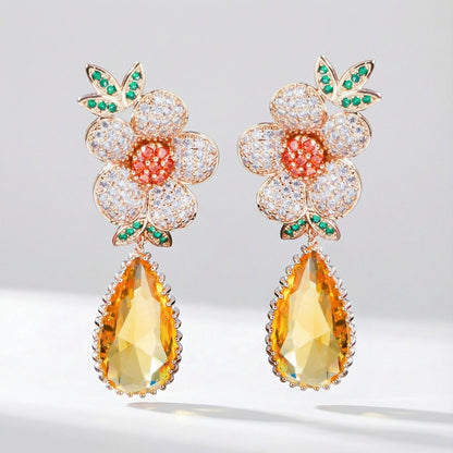 Victoria floral cubic zirconia drop earrings with white petals, orange center, green leaves, and yellow crystal drop