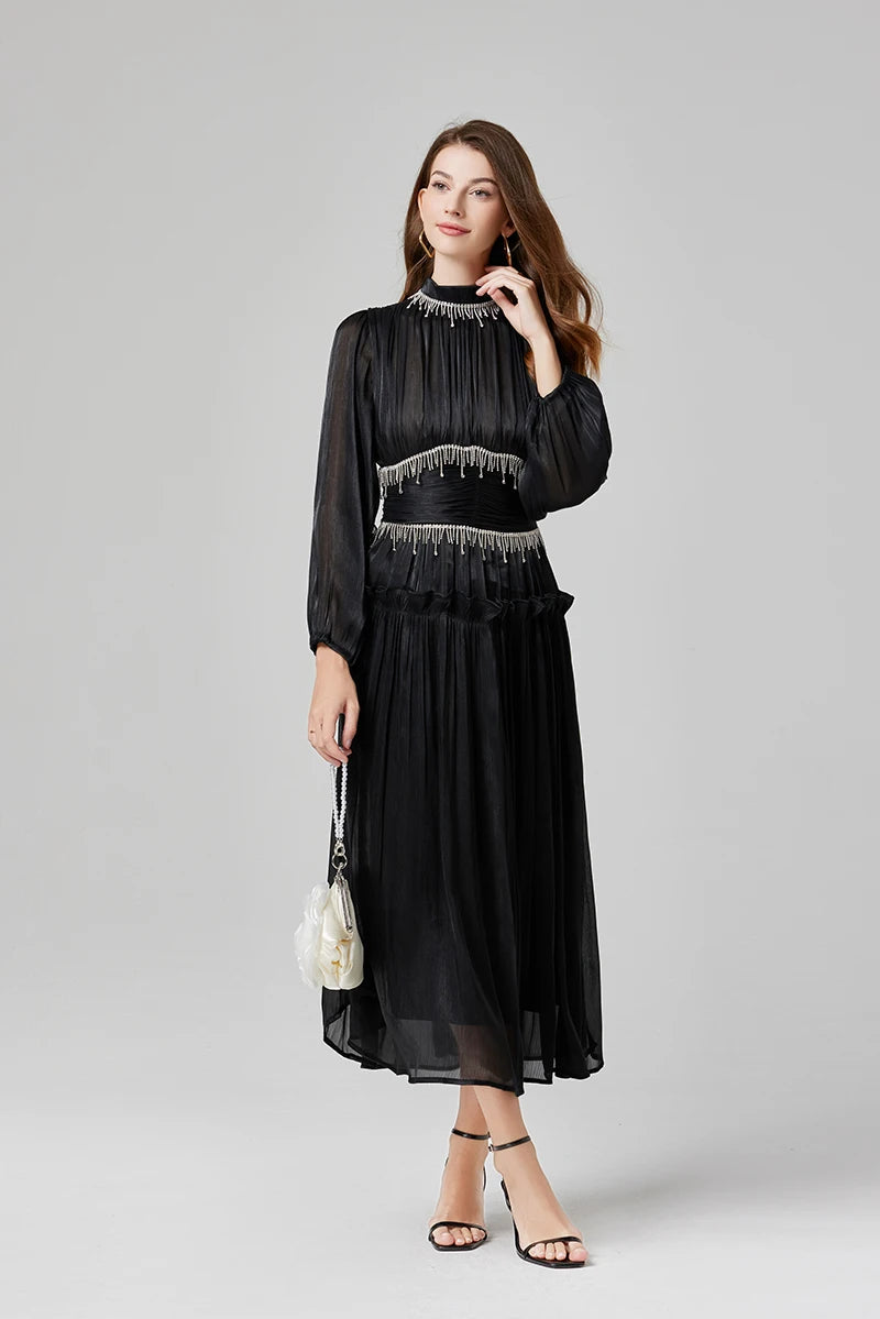 The Victoria maxi dress shown in black, blue, and pink featuring rhinestone fringe waist detailing and long sheer sleeves.