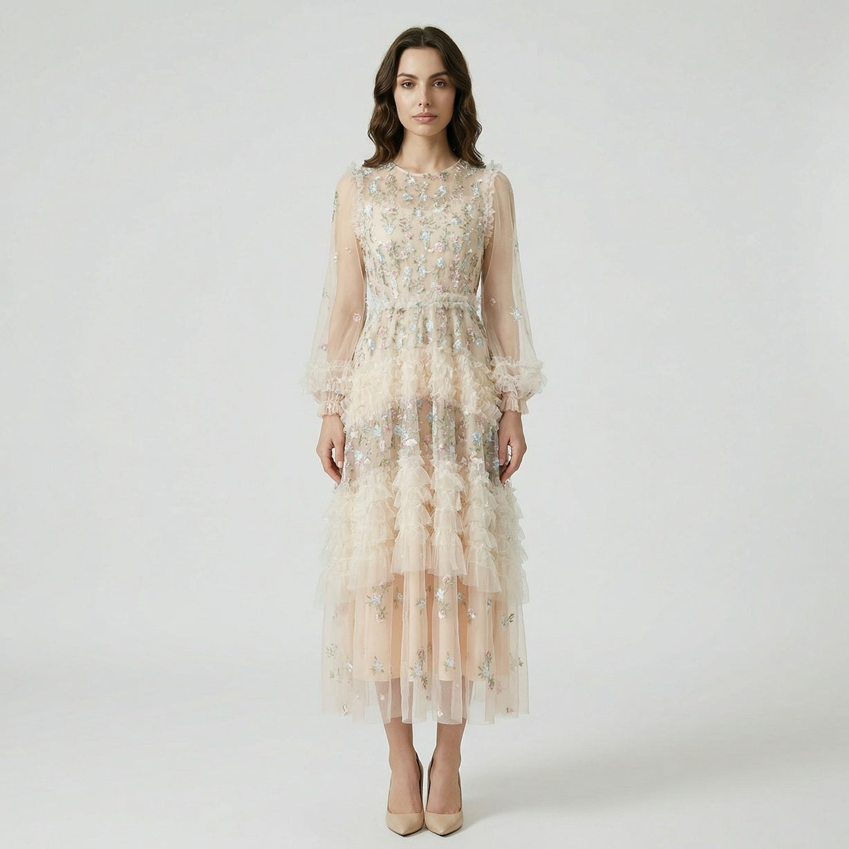 Front view of the Viviane champagne tulle dress featuring pastel floral embroidery, tiered ruffles, and long lantern sleeves displayed on a hanger.