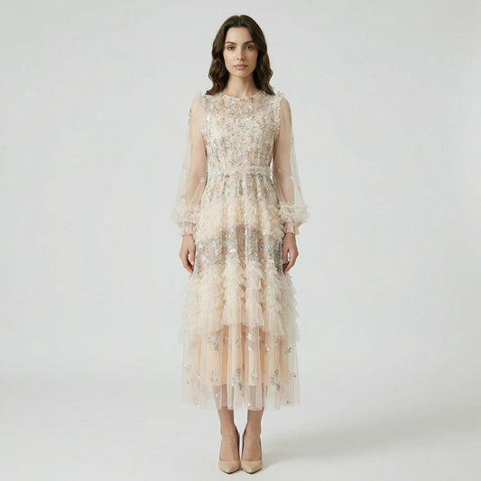 Front view of the Viviane champagne tulle dress featuring pastel floral embroidery, tiered ruffles, and long lantern sleeves displayed on a hanger.